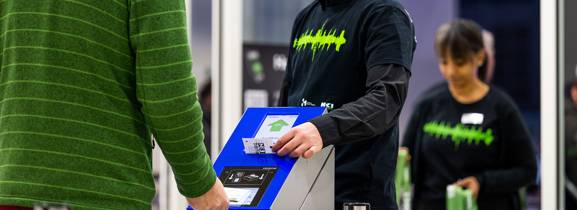Eine Person nutzt eine Ticketmaschine, um für den Eintritt zur Messe zu bezahlen.