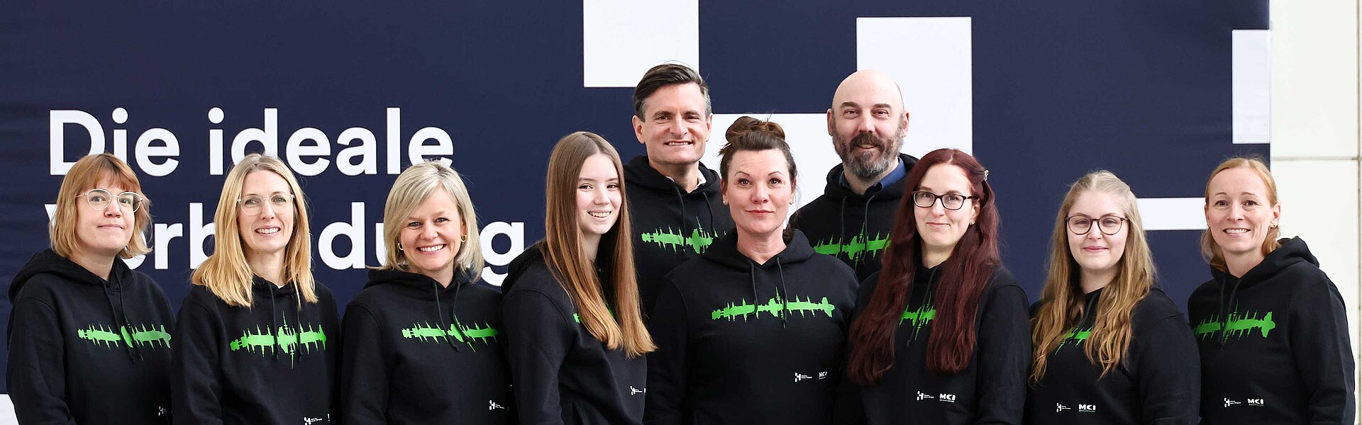 Team der HAMBURG OPEN. Acht Frauen und Männer lächeln in die Kamera. Vor ihnen steht ein Schild mit der Aufschrift: HAMBURG OPEN.