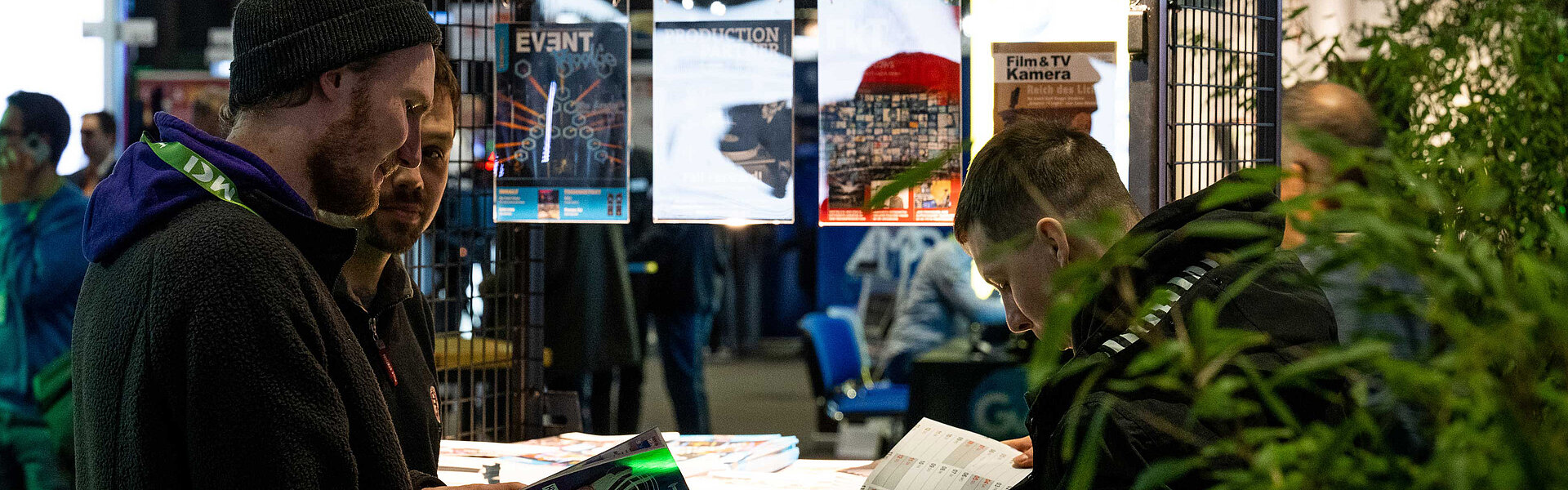 Three people are reading the magazines in the trade press area.