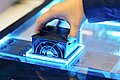 Hand setzt ein technisches Gerät in Form eines Würfels in ein leuchtendes Gehäuse ein.